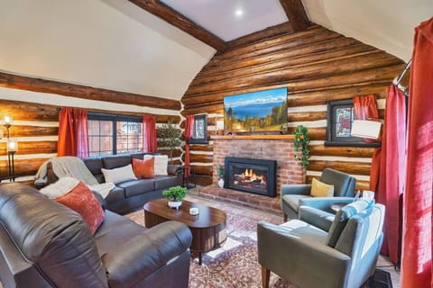 The electric fireplace cast a soft glow across this vaulted log-walled retreat, gathering plush seating around the crackling brick fireplace. Vibrant coral accents against rich wood tones make it a truly memorable place to unwind.
