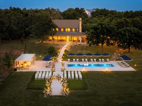 (Manor & pool lit at dusk) House aglow and pool shining in the fading light.
