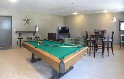 Game room with TV, pool table, game table & pinball machine, pull-out couch.