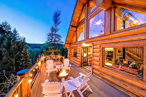 Deck with fire pit, Adirondack chairs, string lights, and tree views