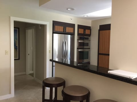 Looking into kitchen with Stainless appliances. Hall to 1/2 bath & master suite.