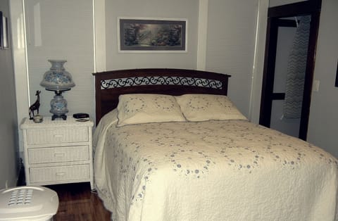 Bedroom #2.  Queen sized bed, white wicker accents, laundry area to the side.