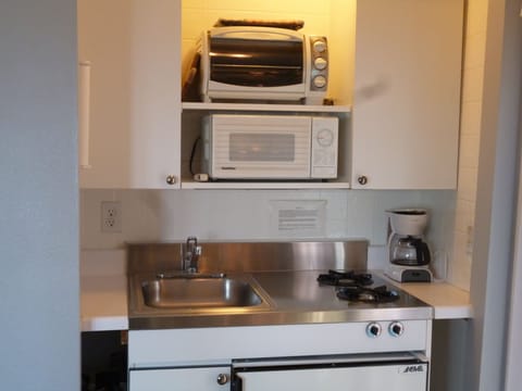 Efficiency kitchenette stocked with kitchenware, utensils. Under counter fridge