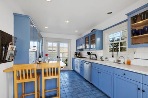 Sunny kitchen with breakfast bar and doors to back lounging area.