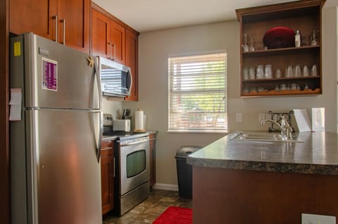 Fully-stocked kitchen with stainless-steel fridge, oven/stove + microwave.