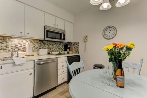 The unit is equipped with a full kitchen, excluding an oven, and features a dining table.