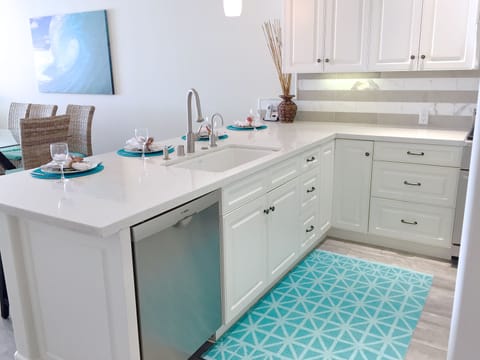 White, bright kitchen with quartz countertops.