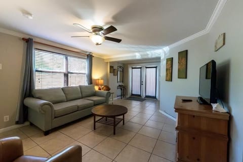 Comfortable living room with double door entry, smart tv and ceiling
 fan. 