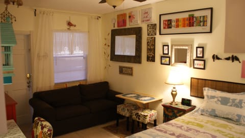 Queen size bed,sofa, wall mounted drop-leaf table and stools for dining.