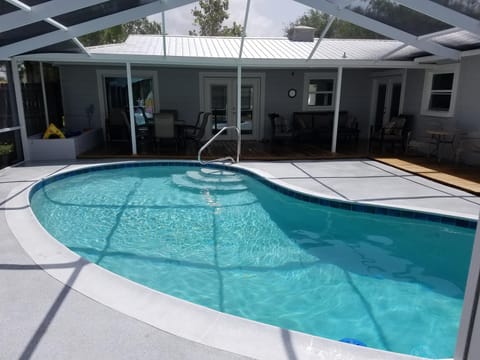 Pool looking to back porch with table to left and large seating area to the right.