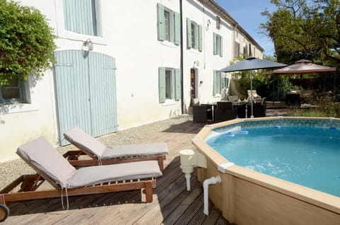 Swimming pool, front of farmhouse, seating and dining area