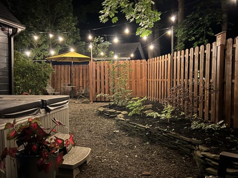 private fenced in hot tub area in back yard with bistro lighting