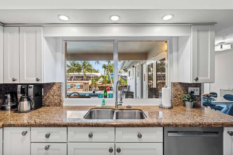 View of pool and canal from kitchen with windows that open up