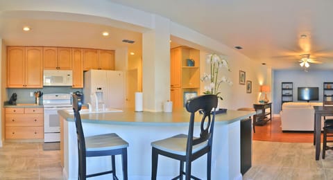 Kitchen with wood cabinetry, bar seating, white appliances, and breakfast counter