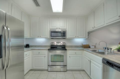 Kitchen – Stainless Appliances & Classic White Cabinetry - This fully equipped St. Simons vacation rental kitchen features stainless steel appliances, a microwave, and plenty of counter space—perfect for shrimp boils, pancake breakfasts, or cocktails before heading to Neptune Park.
