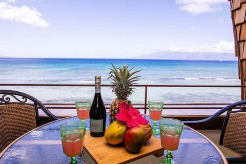 Oceanfront lanai with dining table and panoramic views of turquoise Pacific waters.