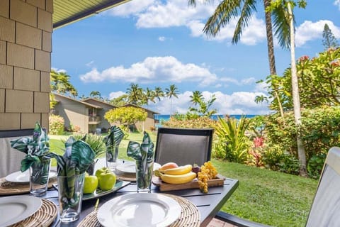 An outdoor dining table set for a relaxed island meal, surrounded by lush gardens and ocean views under bright blue skies.
.