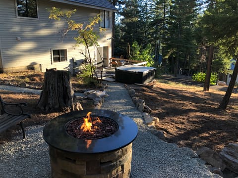 Fire table seating area overlooking deck and spa with lake, mountain view.