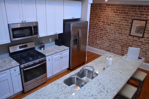 Galley style kitchen with stainless appliances, granite tops, gas stove and breakfast bar
