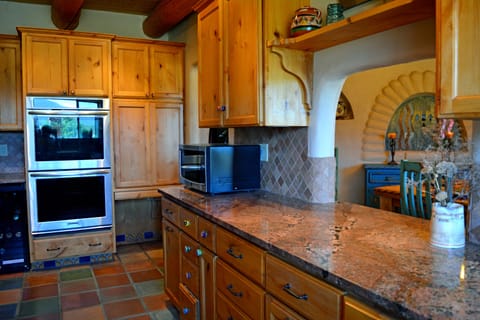 Wine/beverage cooler to left of double built in oven + pass through window between kitchen & dining for ease of serving & clean up