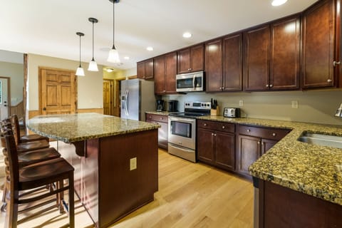 Picture of the kitchen, with center island with chairs, microwave, oven, and refrigerator.