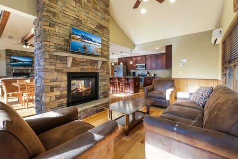The great room of this luxurious Poconos vacation rental, with couches, coffee table, fireplace, and TV.