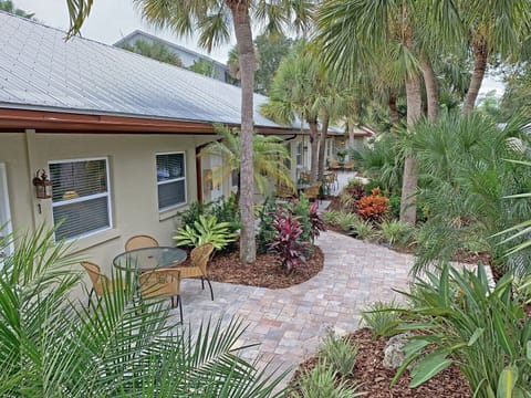 cexterior with patio seating area and lush tropical landscaping