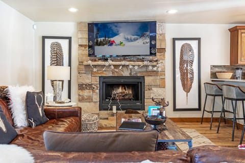 A cozy mountain-style living room with stone fireplace, leather seating, and warm accents designed for relaxing after a day outdoors.