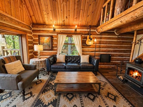 Relax in your cozy log cabin living room with crackling fireplace, plush leather seating, and rustic charm that feels like home.
