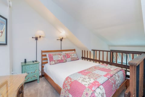 Cozy loft bedroom awaits with crisp linens, warm lighting, and charming patchwork accents—your peaceful retreat after a day of exploring.