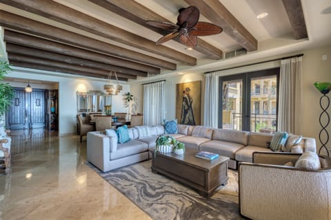 Sink into the plush sectional sofa beneath rustic wood beams and a tropical ceiling fan. Large French doors open to your private balcony, while artwork and thoughtful touches create an inviting escape.