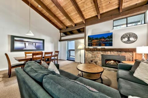 Unwind in your cozy living space with exposed wooden beams, stone fireplace, and comfortable seating for perfect mountain getaway evenings.