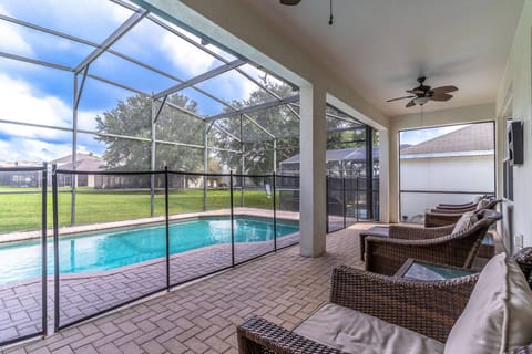 Lounge seating on the rear patio with a fenced in, fully enclosed pool.