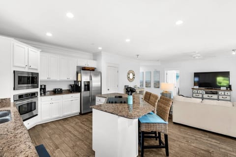 A large kitchen with granite countertops, stainless steel appliances and additional seating at the island