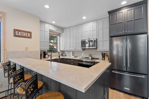 Full kitchen featuring stainless steel appliances, and breakfast bar seating 4.