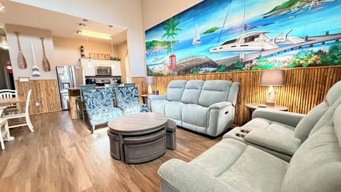 Sink into plush recliners while soaking up tropical vibes from the stunning beach mural. Your open-concept haven flows from cozy living to fully equipped kitchen.