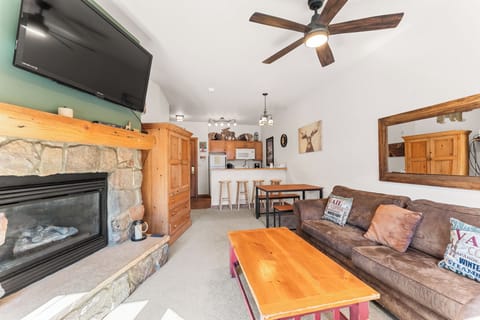 Relax by your cozy stone fireplace while the ceiling fan keeps you comfortable in this mountain-inspired living space.