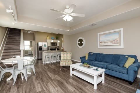 Relax in your stylish open-concept retreat with plush blue seating, modern kitchen, and coastal touches throughout this bright, airy space.