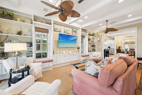 Relax in your elegantly appointed living room, where coastal style meets comfort with built-in shelving and tropical ceiling fans.