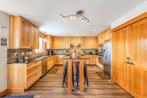 Chef's Kitchen w/ 6 Burner Gas Cook Top, Wall Ovens, and 4 Seating Center Counter Table