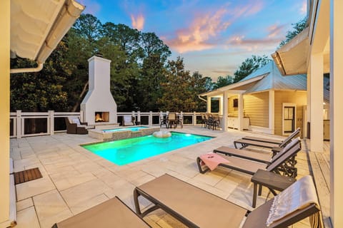 Stunning private pool and covered patio invite you to unwind under soft evening skies, where a crackling outdoor fireplace and plush lounge chairs await your perfect escape.