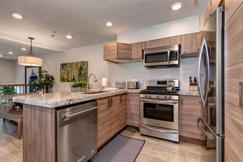 New kitchen with custom cabinets, stainless appliances, 6-burner gas stove, granite counters, and 3 bar seats