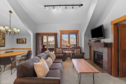 Unwind in your spacious living room with cozy leather seating, crackling fireplace, and stunning mountain views from your private balcony.