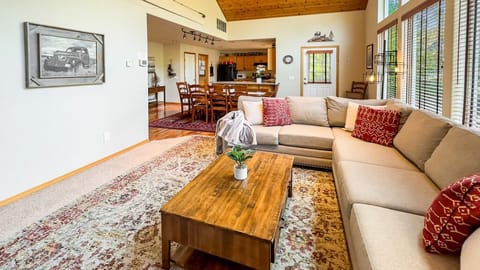 Spacious great room with plush sectional, vaulted wood ceilings, and warm natural flow into the open kitchen