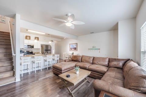 Relax on your spacious sectional sofa while enjoying the open-concept living space with modern kitchen and coastal touches.