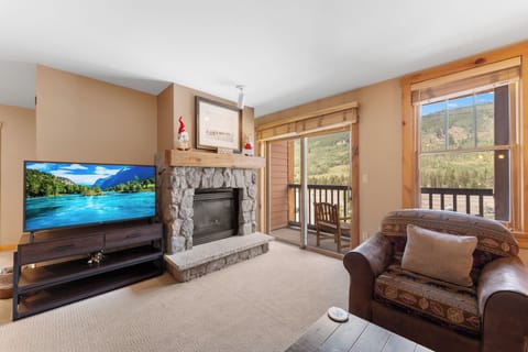 Unwind in your cozy mountain retreat with a stone fireplace, large TV, and stunning forest views from your private balcony.