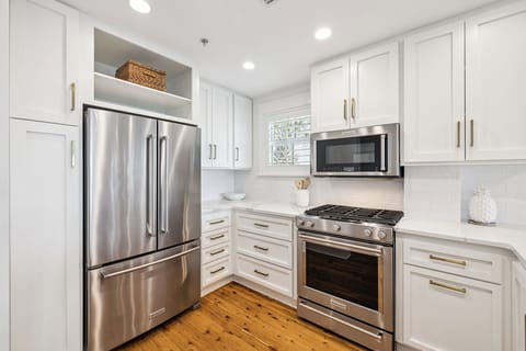 Step into your fully equipped kitchen featuring stainless steel appliances, pristine white cabinetry, and warm wood floors perfect for your culinary adventures.