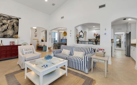 Relax in this charming coastal living space with its nautical-striped sofa, beach house charm, and open archways leading to your dining area.