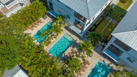 Your private sanctuary unfolds under twilight skies—two shimmering pools invite endless evening swims, surrounded by glowing palms and cozy lanai spaces.