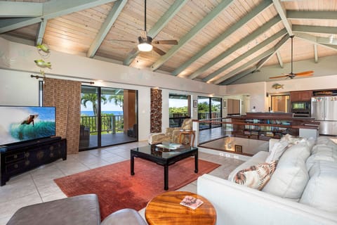 The expansive upstairs living area has soaring wood beamed ceilings, indirect lighting, ocean views